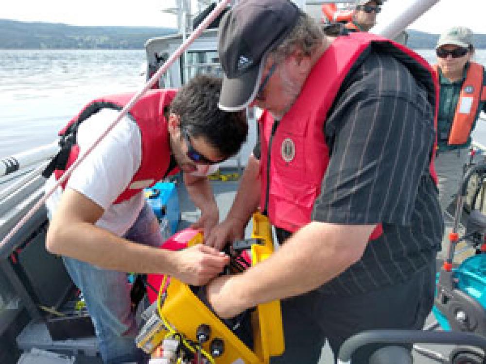 Two men handling a technical device in a boat