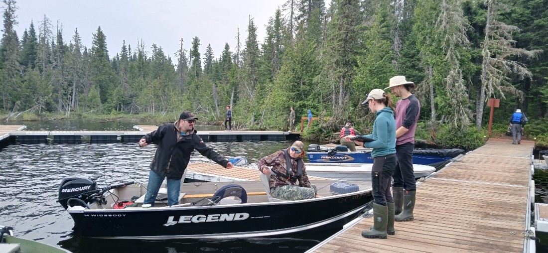 Two of the Aquatic Invasive Species Awareness Team chat with two boaters in their dockside boat.
