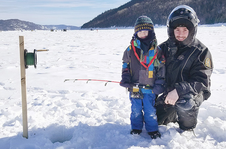 Un agent des pêches avec un enfant qui pêche dans le fjord du Saguenay