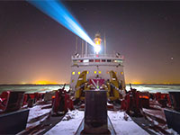 Photo de nuit de l'arrière d'un navire muni d'un puissant projecteur