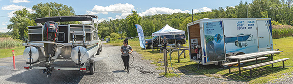 A DFO employee cleans a boat at an information booth on aquatic invasive