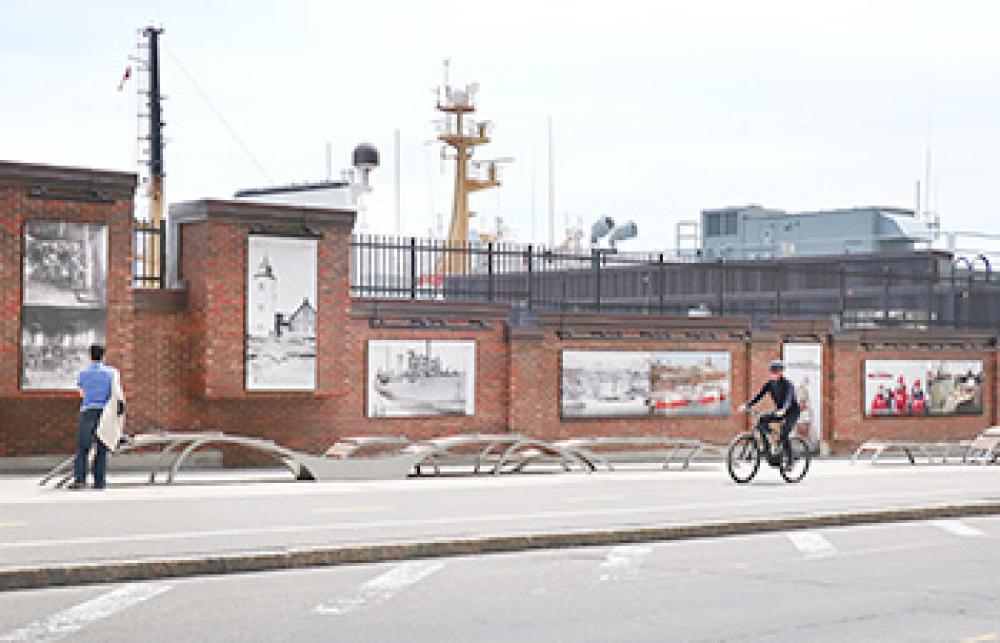 Photo montrant l’aire de repos. On peut y voir un marcheur observer les photos et un cycliste rouler sur la piste cyclable.