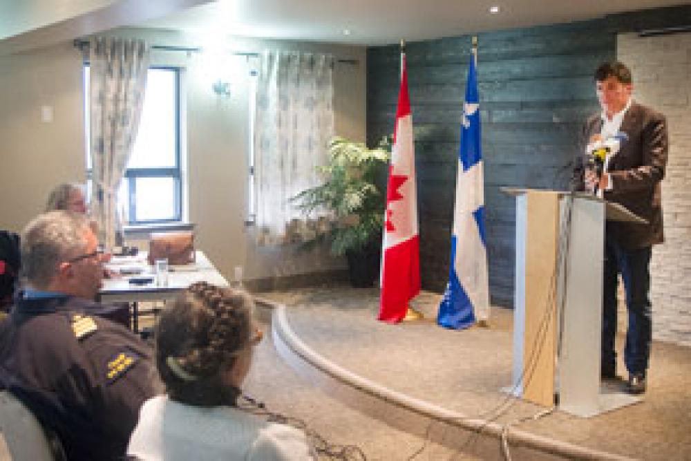 Photo du ministre Dominic LeBlanc au lutrin et d'une partie de l'auditoire pendant la conférence de presse aux Îles-de-la-Madeleine