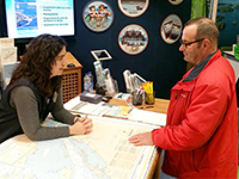 Au stand du Service hydrographique du Canada, une hydrographe discute avec un visiteur